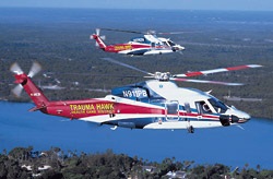 Two Trauma Hawk helicopters flying side by side over water.