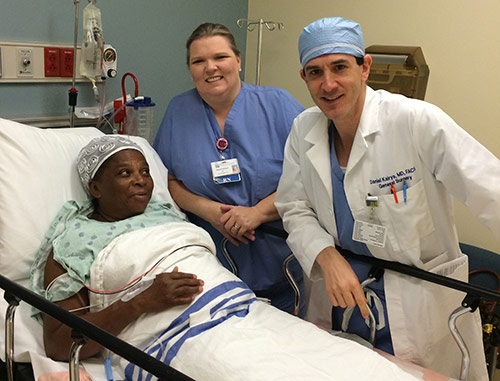 Doctor Daniel Kairys and nurse Pam Ellison stand next to a patient in bed