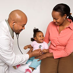 A doctor listens to the heart beat of a small girl with the mother sitting next to her