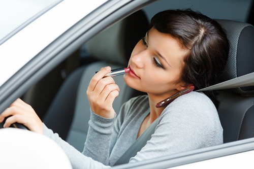 A young woman applying makeup in the car while driving