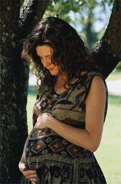 Pregnant woman standing by a tree
