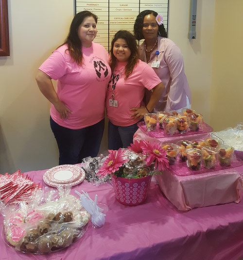 Team leaders in pink shirts stand behind a table covered in a pink table cloth