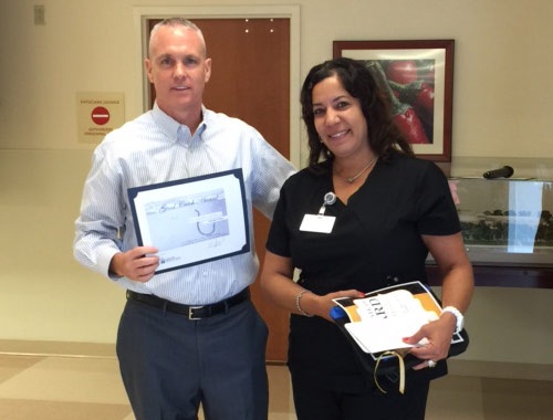 Richard holding the employee of the month certificate about to present it to Annette to his right