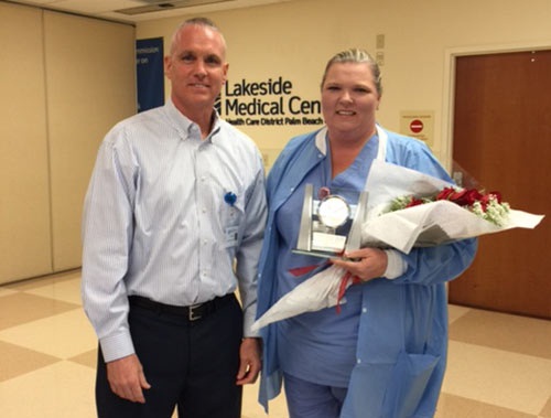 Rick Roche and Pam Ellison. Pam is holding a commemorative clock and flowers