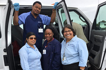 Four Brumback Clinic staff stand by the side of a white van with open doors