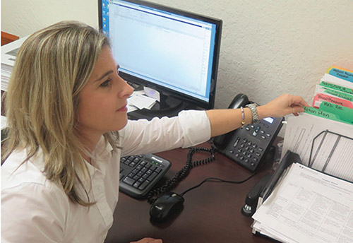 Ingrid pulling a file in an organizer on top of her desk.