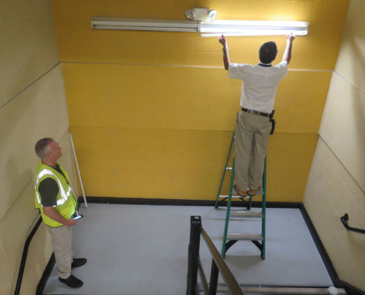 Al changing a light bulb in the stair well while Rick watches