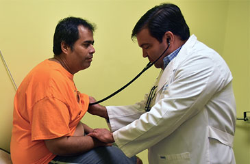 Daniel Perez, MD listens to a Puerto Rican evacuees chest with a stethoscope.