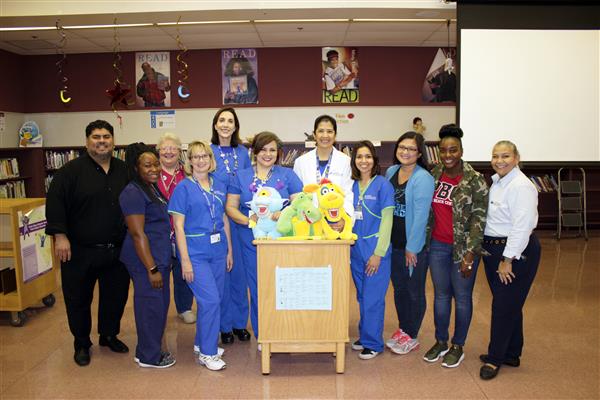 Brumback Dental staff stands at a podium with blue, green and yellow stuffed animals on top of it.