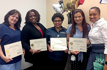 The Patient Navigators stand together holding up their C H W training certificates.