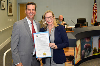 Darcy J Davis holds the proclamation while having a photo taken with Mayor Todd Wodraska