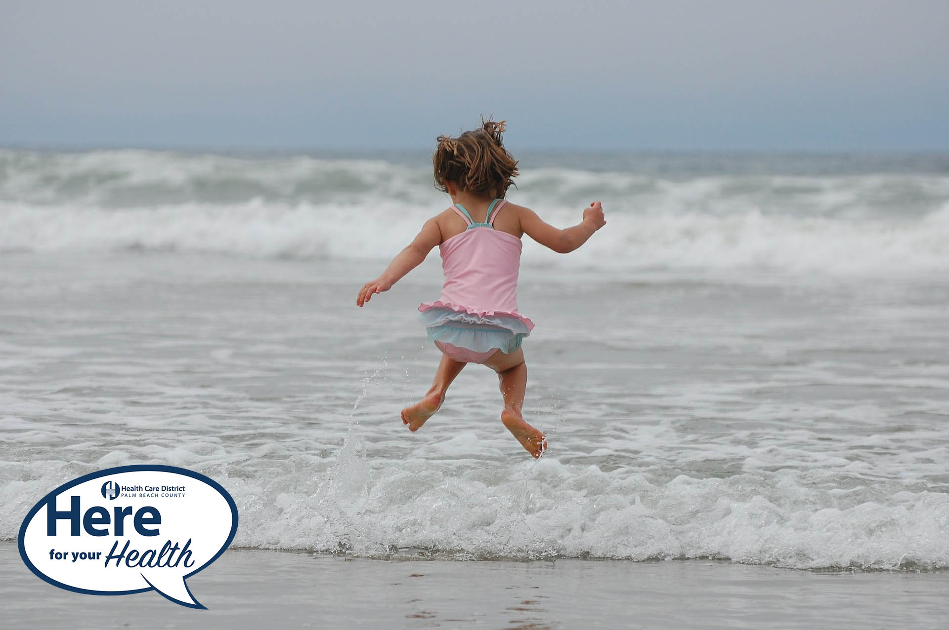 A little girl jumps in the ocean