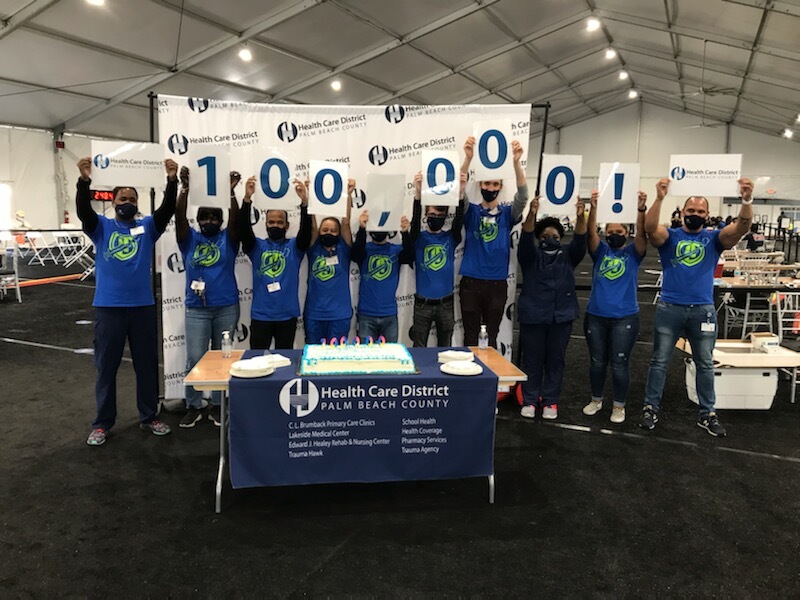Staff members celebrating 100,000 vaccinations