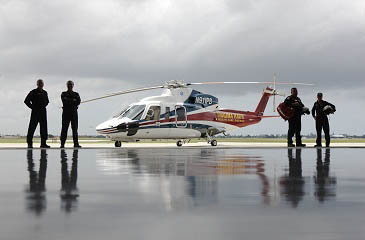Trauma Hawk Flight Team standing in the Aeromedical hanger with the Trauma Hawk behind them.
