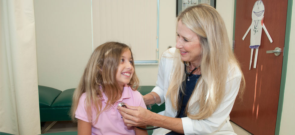 A school nurse listens to the heart beat of a little girl