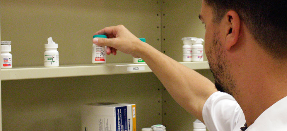 A pharmacist grabs medication from a shelf